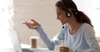 Femme souriante, millénaire, freelance, portant un casque d'écoute, communiquant avec un client